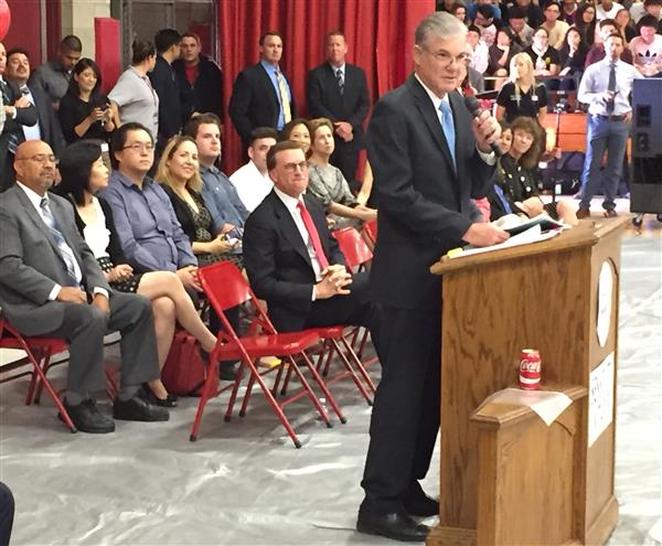 State Superintendent Tom Torlakson speaking at a podiium. Several adults sit behind him listening.